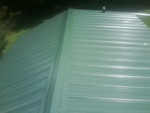 New green metal panels meeting at the ridge of a roof — Flat Roof Repair work by our crew in Palisade